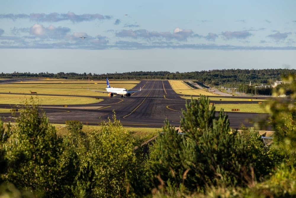 Passagerarflygplan rullar på Arlanda flygplats, omgivet av grönska – Uppsala ligger bara 30 minuter härifrån.
