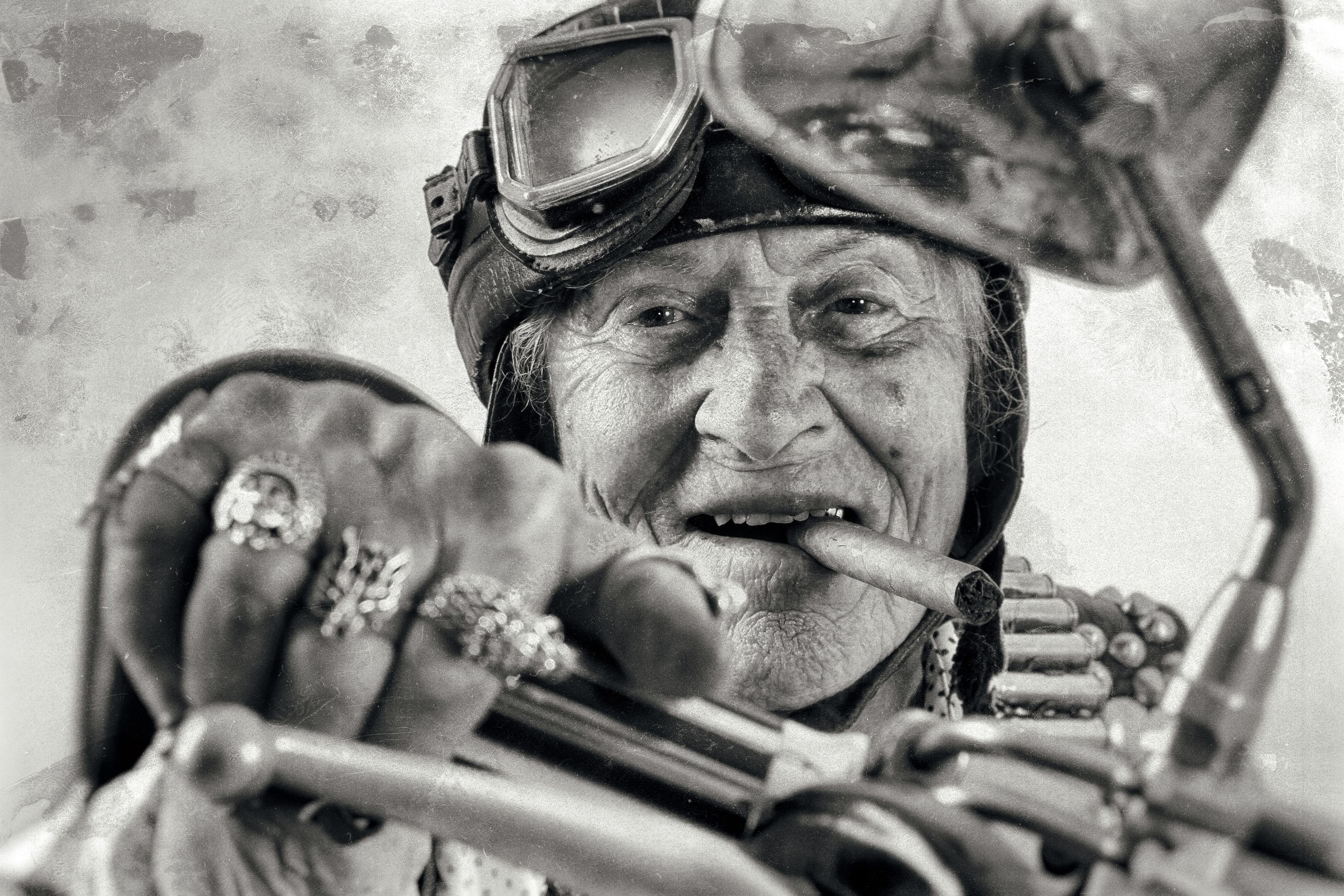 Old man riding a motorcycle and smoking a cigarre