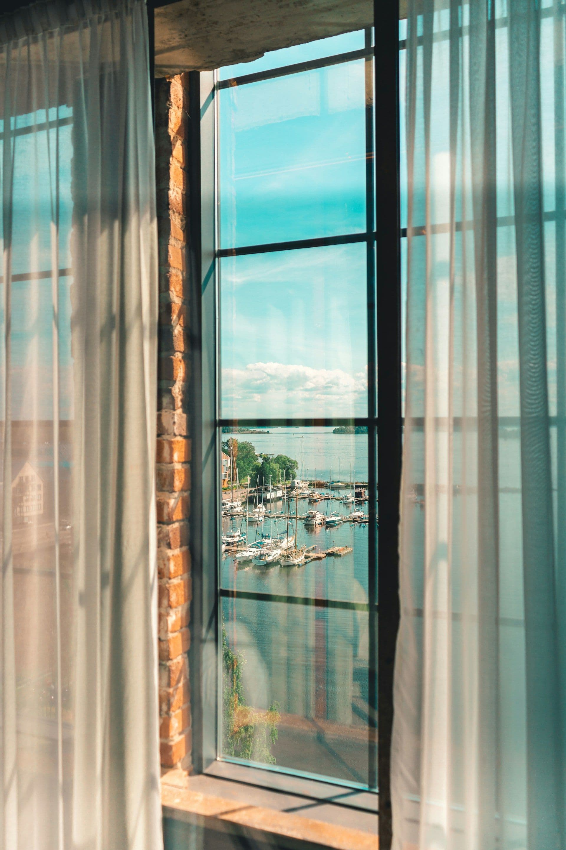 Utsikt över Västerås småbåtshamn och Mälaren genom ett hotellfönster.